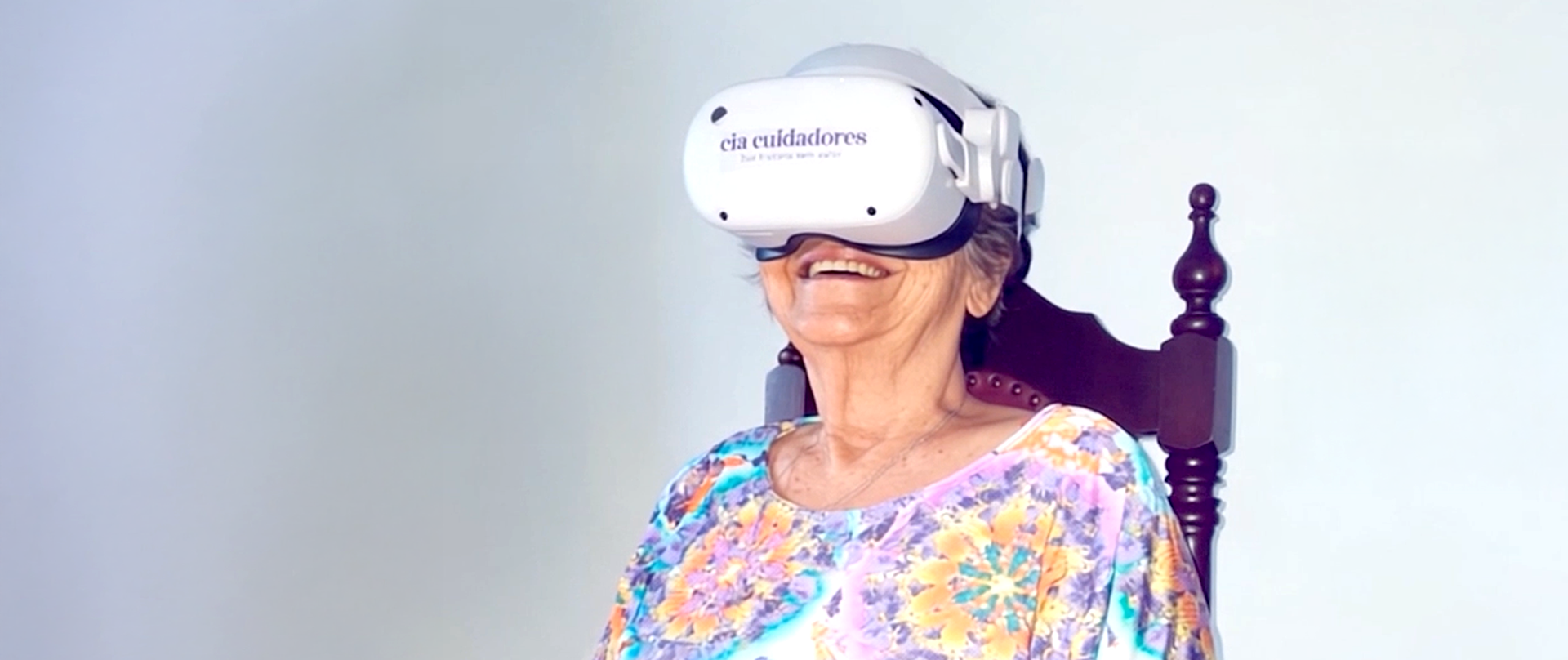 Pessoa idosa sorrindo enquanto usa óculos de realidade virtual
